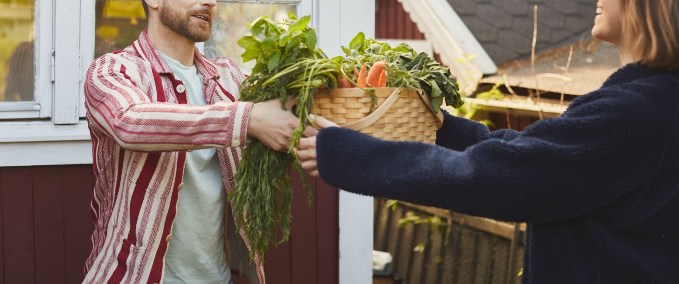 En man som lämnar över en korg med grönsaker till en kvinna
