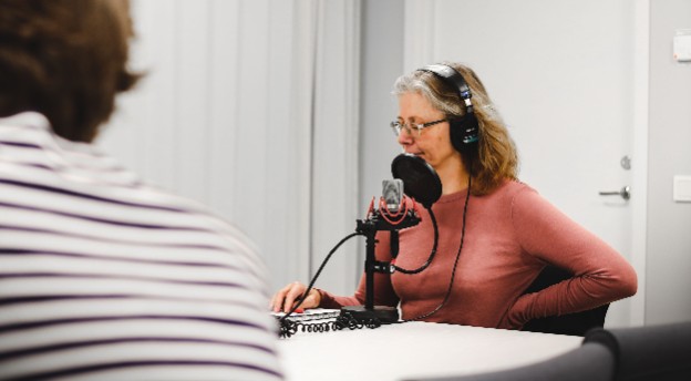 En kvinna med hörlurar som pratar in i en mikrofon